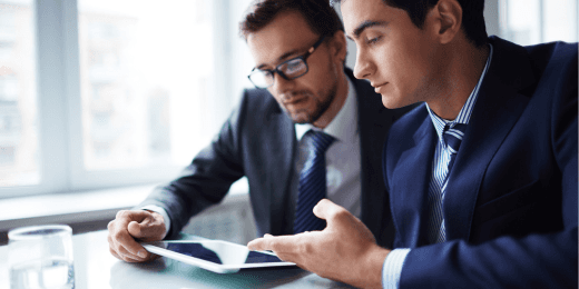 Two business men looking at stakeholder analytics on a tablet.