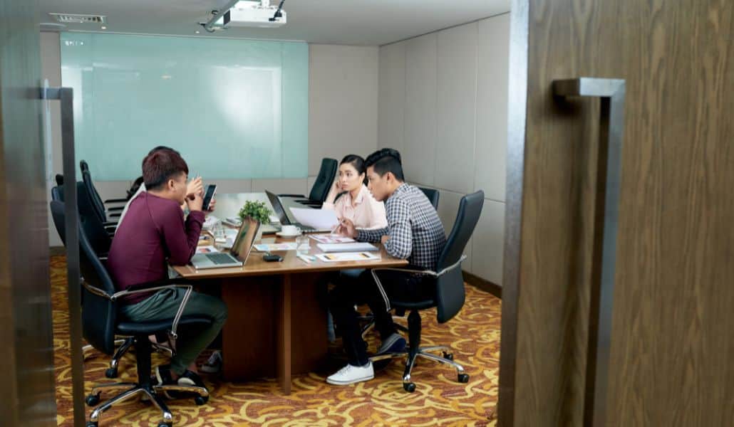 A group of office employees discussing how to prepare for ISO 9001:2026 certification in a meeting room