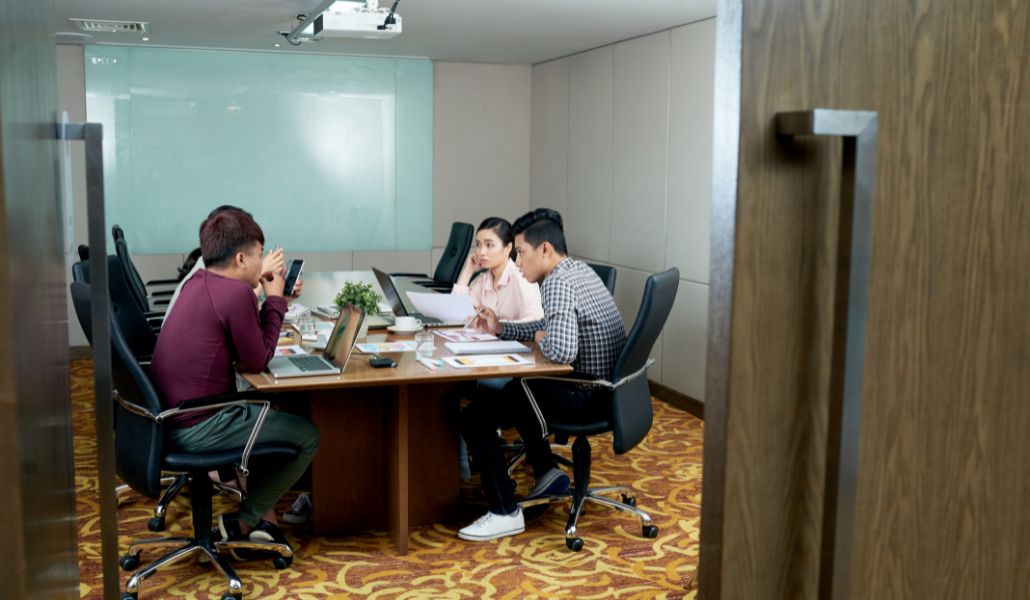 A group of office employees discussing how to prepare for ISO 9001:2026 certification in a meeting room