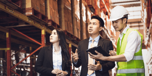 Warehouse workers and managers discussing operations while reviewing information on a tablet.