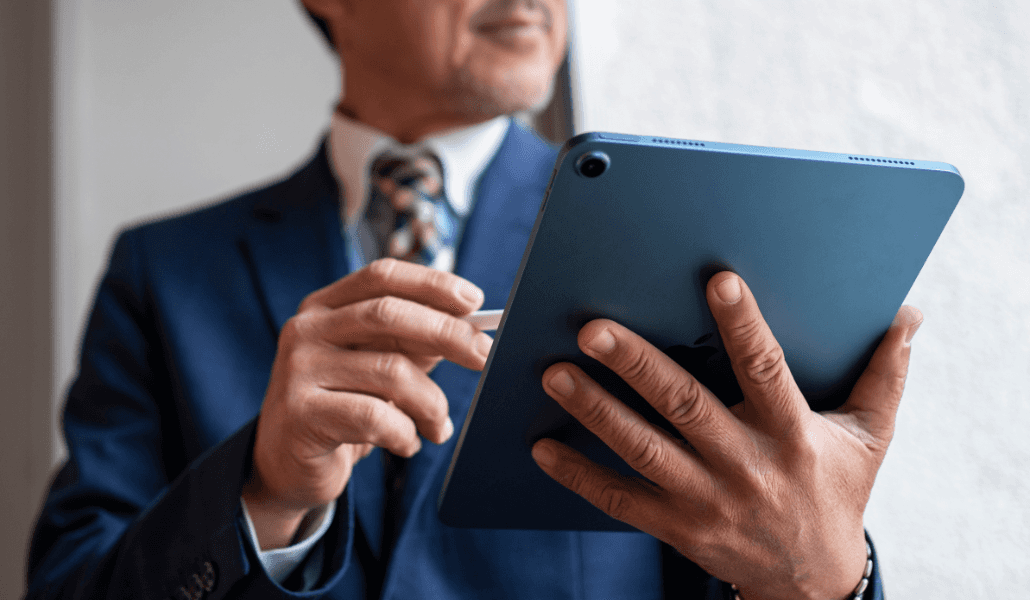 A business professional in a suit holding a tablet and stylus.