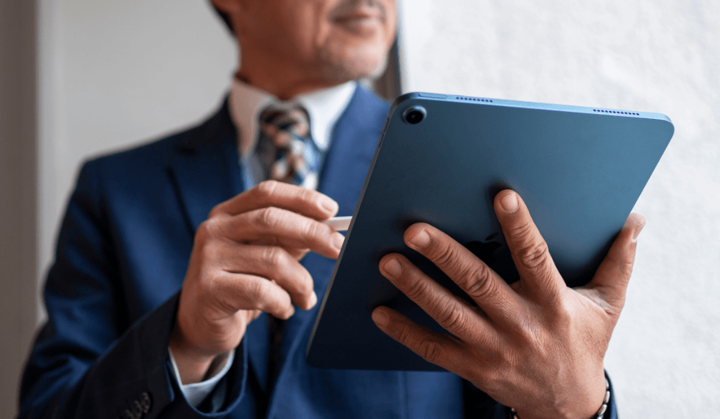 A business professional in a suit holding a tablet and stylus.