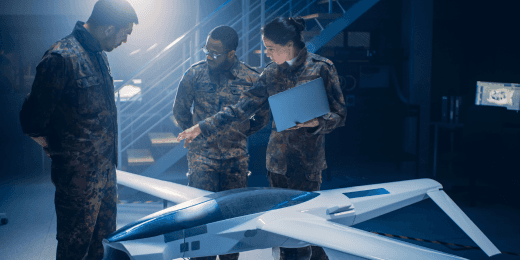 Military personnel in camouflage uniforms examining a large drone prototype in a research and development facility.