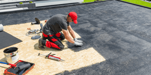 A worker installs a protective sealant layer on a rooftop to ensure effective waterproofing in construction.