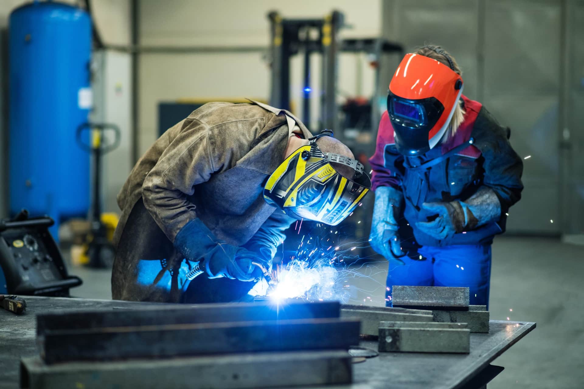 Two welders in protective welding gear working on a project.