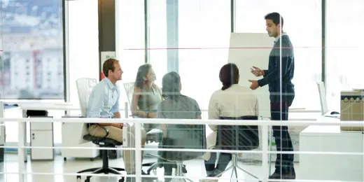 Business team in a modern office having a meeting, with one person presenting at a flip chart.