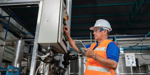 A safety officer operating an industrial control panel during a plant inspection.