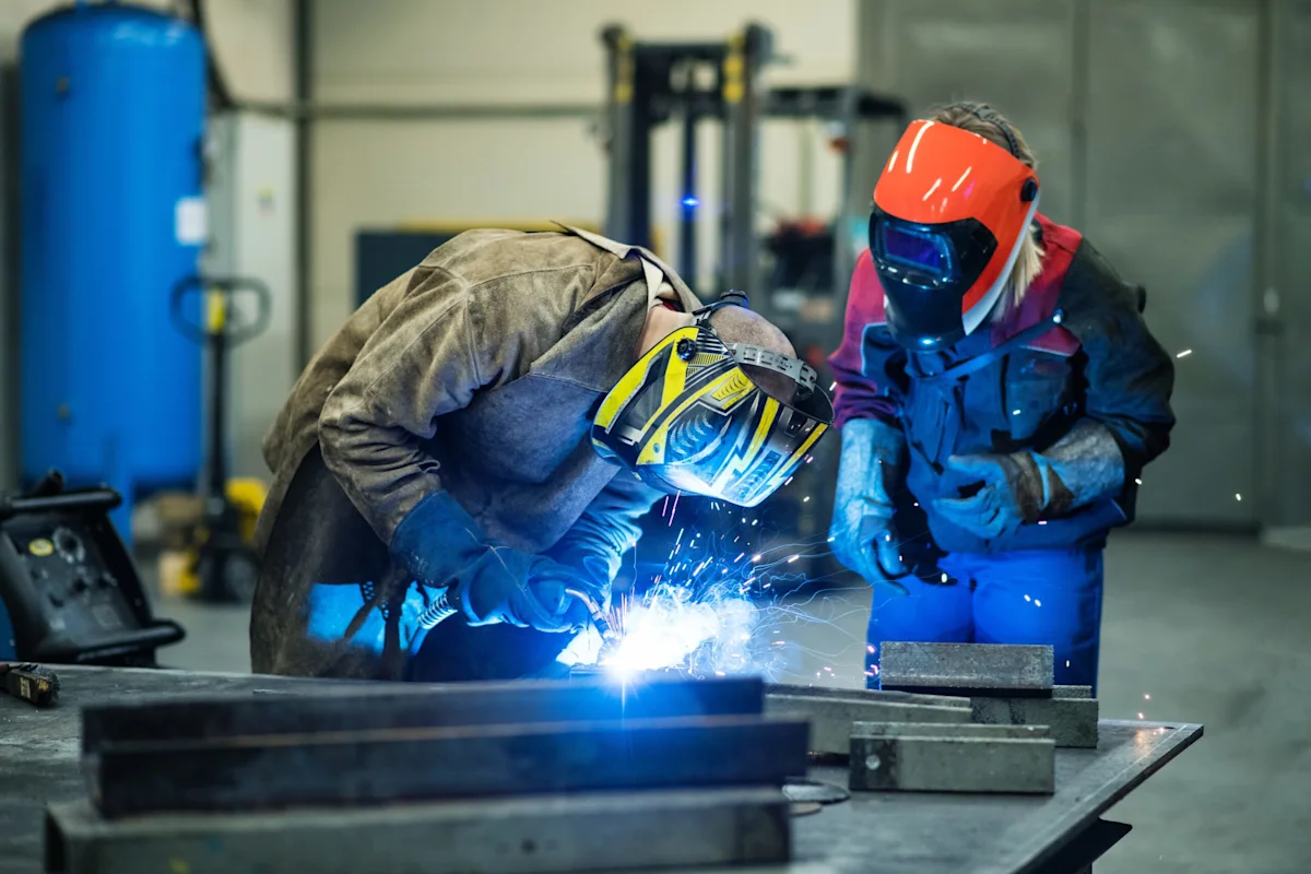 Two welders in protective welding gear working on a project.