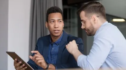 2 employees doing peer evaluation using a peer evaluation form on a tablet|Peer Evaluation Form Sample Report|Formulario de evaluación